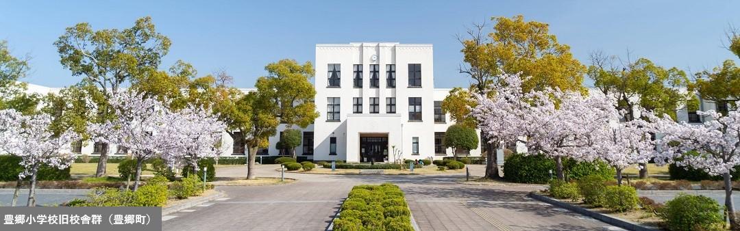 草木が芽吹き、桜が咲き始めている豊郷小学校旧校舎の写真