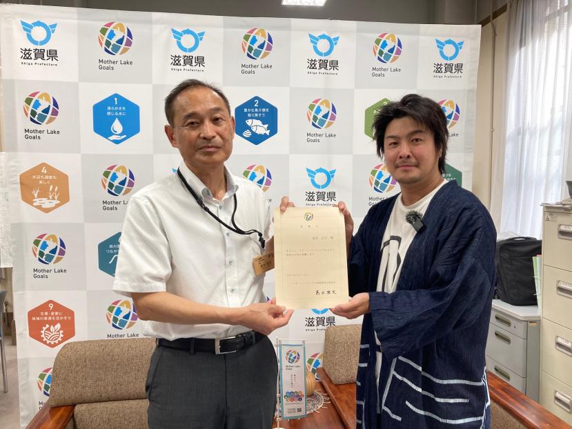 マザーレイクゴールズふるさと活性化大使委嘱状を受け取る様子