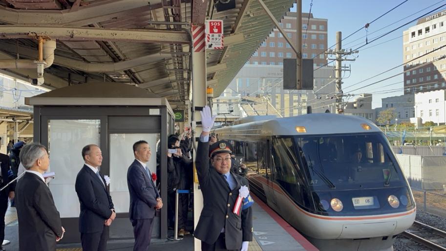 出発の合図をする草津駅長と、お見送りをする三日月知事ら