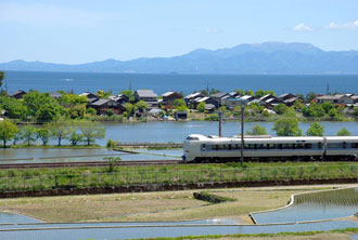 写真:琵琶湖をバックに走る電車