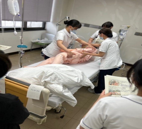 人形を使い、ベッド上で人口呼吸器の装着時の体位交換する演習風景