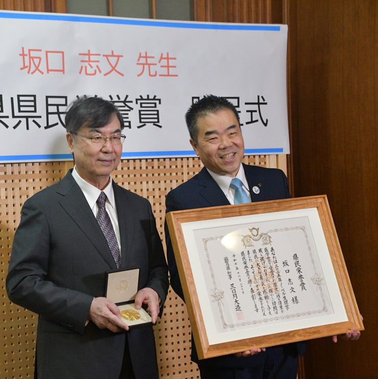 知事室でノーベル賞のメダルを手にもつ坂口教授(左)