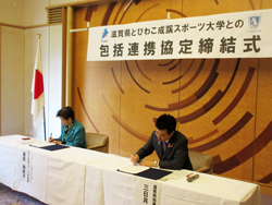 びわこ成蹊スポーツ大学との包括連携協定締結式にて協定への署名を行う様子