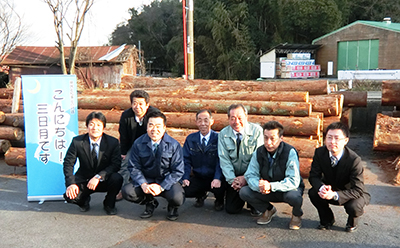 「こんにちは!三日月です」と書かれた立て看板の横で撮られた、大津・南部地域木材供給協議会の皆さんと三日月知事の集合写真